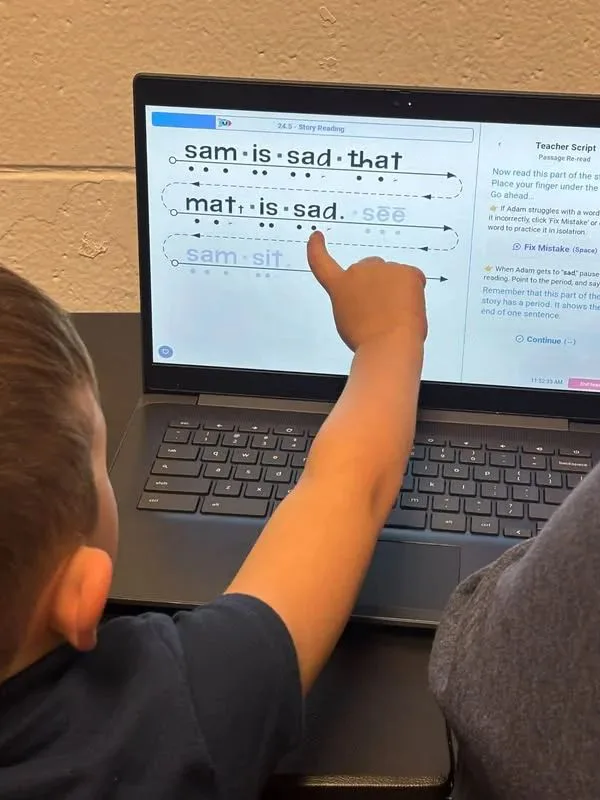 A student pointing at a word on a laptop during a Once lesson